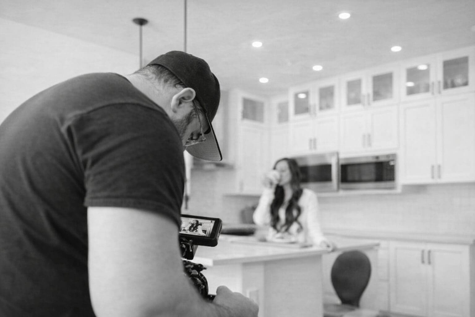 Looking over the shoulder of a man filming a woman drinking coffee